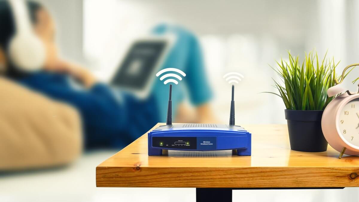 how to choose routers - closeup of a wireless router and a man using smartphone on livin